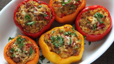 Enjoy a delightful stuffed peppers recipe featuring five colorful bell peppers filled with a savory meatball mixture, topped with melted cheese and chopped parsley, all beautifully presented in a white oval baking dish. _MamaMancinis