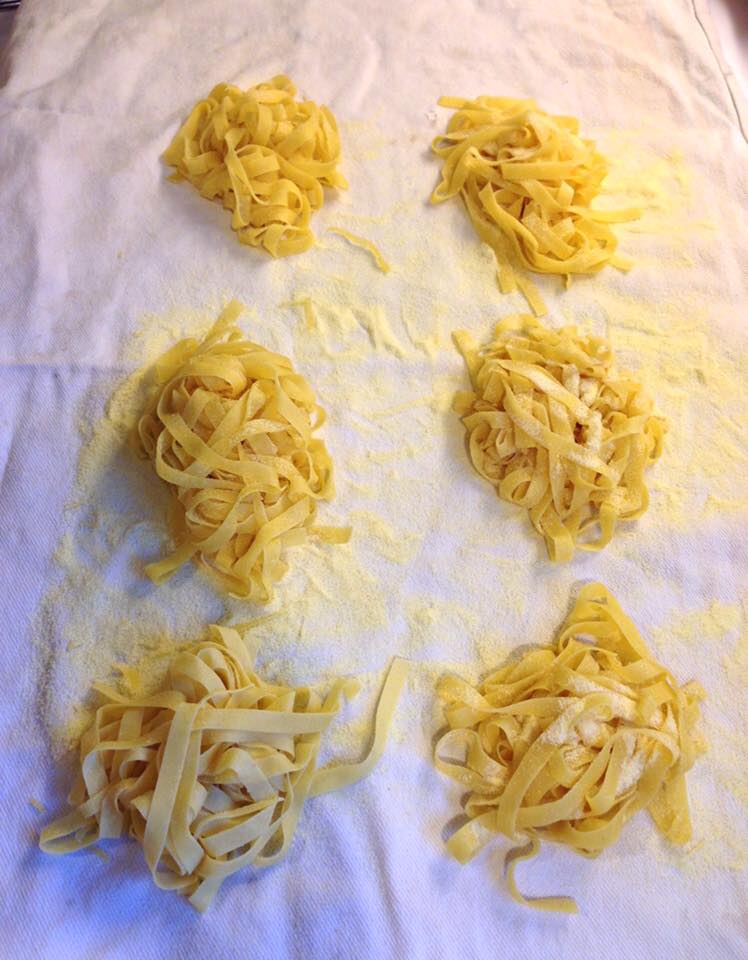 Freshly made semolina pasta tagliatelle nests are arranged on a floured white cloth, ready to dry. _MamaMancinis